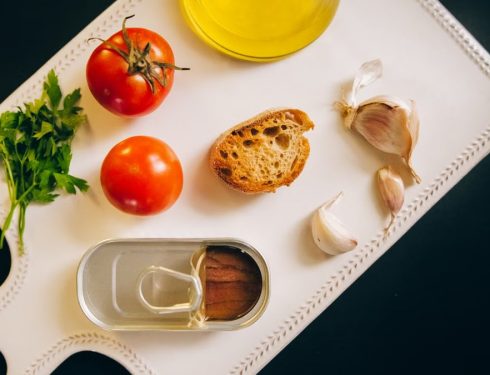 Fresh ingredients for making Catalán toast, including tomatoes, anchovies, and garlic.